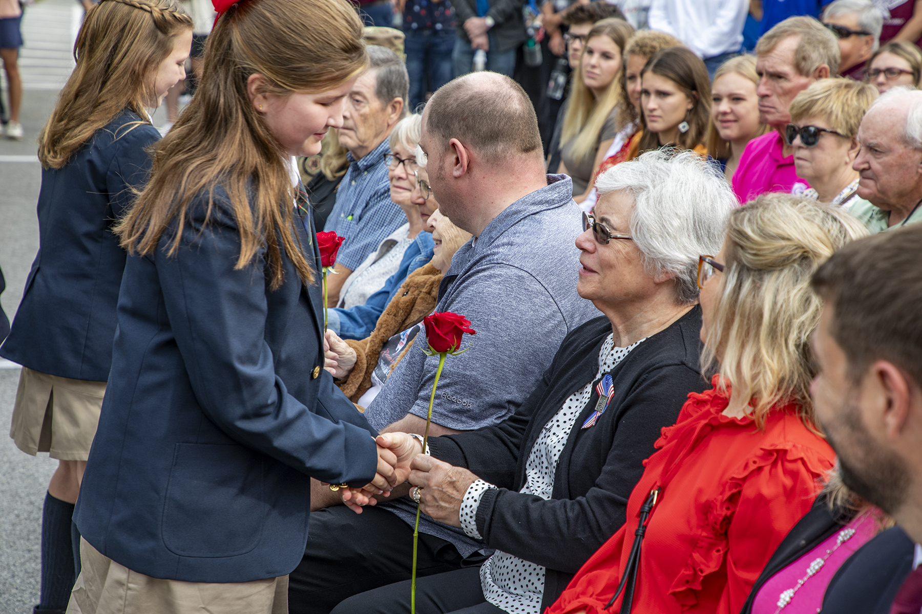 Girl hands an older woman a red rose