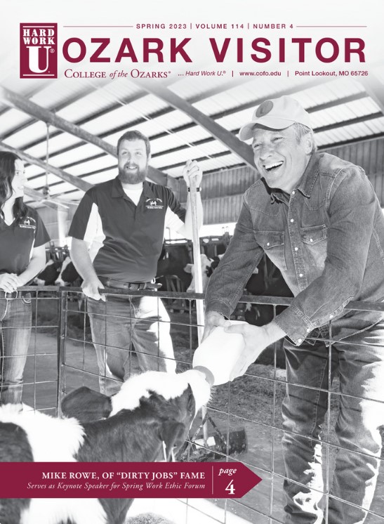 Man feeds a calf while a man and woman look on
